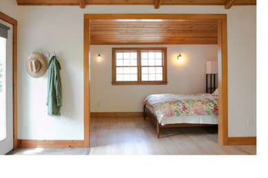 Diseño de dormitorio campestre pequeño con paredes beige, suelo laminado y suelo beige