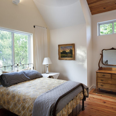 Example of a farmhouse medium tone wood floor bedroom design in Austin with white walls