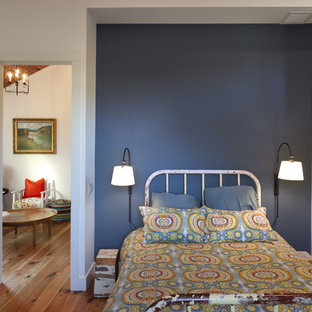 Imagen de habitación de invitados campestre, sin chimenea, con paredes azules y suelo de madera en tonos medios