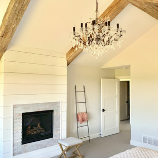 Cette image montre une grand chambre rustique avec un mur gris, une cheminée standard, un manteau de cheminée en brique et un sol gris.