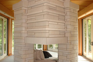 Example of a minimalist bedroom design in Other with a two-sided fireplace and a stone fireplace