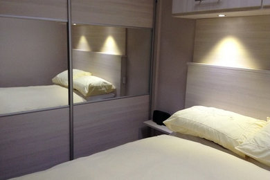 Diseño de dormitorio principal moderno pequeño con paredes beige y suelo de madera clara