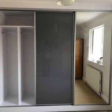 Fitted wardrobe with grey glass and mirror doors.