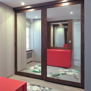 Diseño de habitación de invitados actual, de tamaño medio, sin chimenea, con paredes beige, suelo de madera clara y marco de chimenea de madera