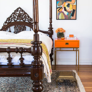 Inspiration for an expansive eclectic master bedroom in Melbourne with white walls, medium hardwood floors and brown floor.