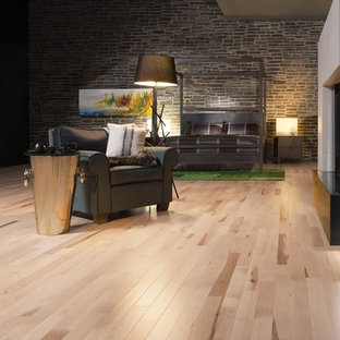 Imagen de dormitorio tipo loft, urbano, grande, con paredes grises, suelo de madera clara, chimenea de doble cara y marco de chimenea de hormigón