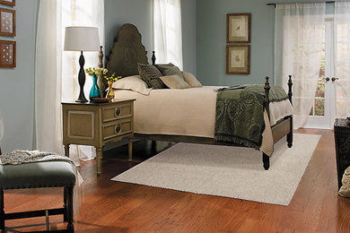 Modelo de dormitorio principal clásico de tamaño medio con paredes azules y suelo de madera en tonos medios
