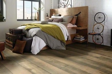 Large urban master vinyl floor and brown floor bedroom photo in Other with white walls and no fireplace