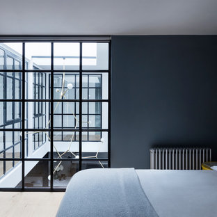 Modelo de dormitorio urbano, de tamaño medio, con suelo de madera clara