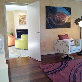 Ejemplo de habitación de invitados industrial, grande, con paredes beige, suelo de madera oscura, chimenea tradicional, marco de chimenea de piedra y suelo rojo