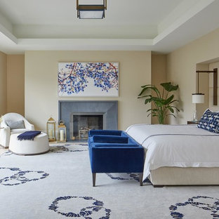 Idee per una grande camera matrimoniale chic con pareti beige, parquet chiaro, camino classico, cornice del camino in cemento e pavimento beige
