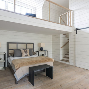 Diseño de dormitorio tipo loft, de estilo de casa de campo, grande, con paredes blancas y marco de chimenea de piedra