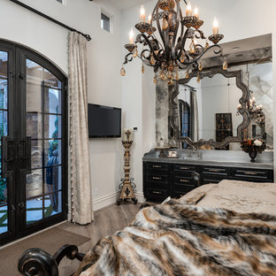 Ejemplo de habitación de invitados romántica, extra grande, con paredes blancas, suelo de madera oscura, chimenea de doble cara, marco de chimenea de piedra y suelo marrón