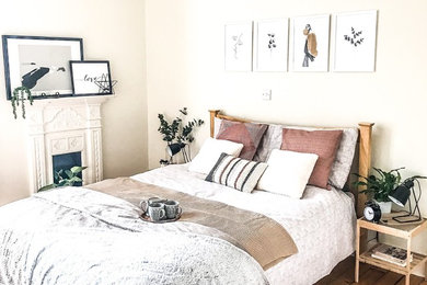 エディンバラにある中くらいな北欧スタイルのおしゃれな主寝室 (白い壁、淡色無垢フローリング、標準型暖炉、漆喰の暖炉まわり、茶色い床) のレイアウト
