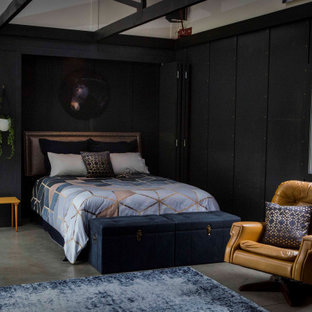Imagen de habitación de invitados boiserie, urbana, grande, con paredes negras, suelo de cemento, suelo gris y boiserie