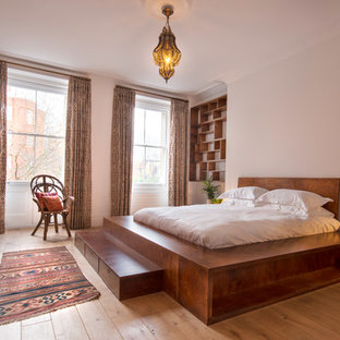 Inspiration for a large mediterranean master bedroom in London with white walls, light hardwood flooring and beige floors.