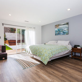 Foto de dormitorio principal, contemporáneo, grande, sin chimenea, con paredes blancas, suelo de madera en tonos medios, marco de chimenea de hormigón y suelo marrón