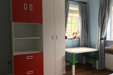 Imagen de dormitorio de tamaño medio con paredes azules, suelo de madera en tonos medios y suelo marrón