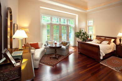 Ejemplo de dormitorio principal clásico grande sin chimenea con paredes beige y suelo de madera oscura