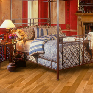 Esempio di una camera matrimoniale design di medie dimensioni con pareti rosse, parquet chiaro, camino classico, cornice del camino in legno e pavimento beige
