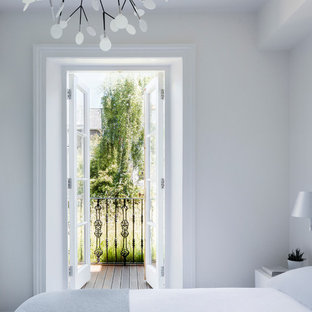 Modelo de dormitorio principal, actual, pequeño, con paredes blancas y suelo de madera oscura