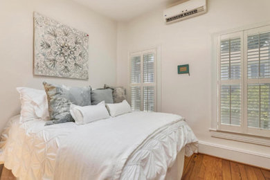 Ejemplo de habitación de invitados romántica de tamaño medio sin chimenea con paredes blancas, suelo de madera oscura y suelo marrón