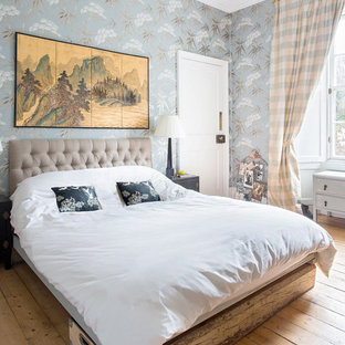 This is an example of a medium sized eclectic master bedroom in Edinburgh with multi-coloured walls, medium hardwood flooring and brown floors.