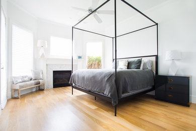 Modernes Schlafzimmer mit weißer Wandfarbe, braunem Holzboden, Kamin, Kaminumrandung aus Stein und braunem Boden in Dallas