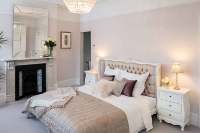 Inspiration for a classic bedroom in London with pink walls, carpet, a standard fireplace and beige floors.