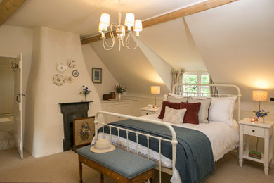 Photo of a medium sized farmhouse master bedroom in Dorset with beige walls, carpet, a standard fireplace, a metal fireplace surround and beige floors.