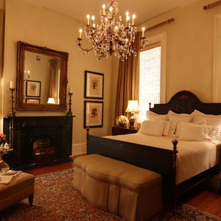 Ejemplo de habitación de invitados clásica, grande, con paredes beige, suelo de madera oscura, chimenea tradicional y marco de chimenea de yeso