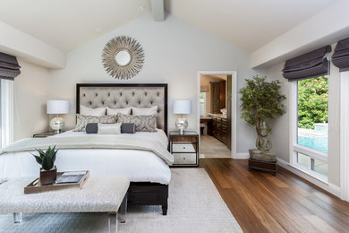 Imagen de dormitorio principal clásico renovado grande sin chimenea con paredes grises y suelo de madera en tonos medios
