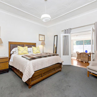 This is an example of a country guest bedroom in Other with white walls, carpet and grey floor.