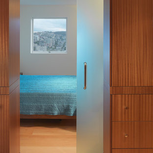 Modelo de dormitorio minimalista, de tamaño medio, con paredes grises, suelo de madera clara y suelo marrón