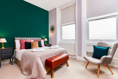 Large contemporary master bedroom in London with green walls and carpet.