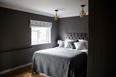 Foto de dormitorio principal actual de tamaño medio con paredes grises, suelo de madera en tonos medios y suelo marrón
