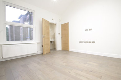 Imagen de habitación de invitados actual grande sin chimenea con paredes blancas, suelo de madera en tonos medios y suelo gris