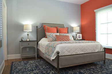 Ejemplo de habitación de invitados clásica renovada de tamaño medio sin chimenea con parades naranjas, suelo de madera en tonos medios y suelo marrón