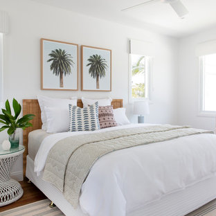 Inspiration for a large beach style guest bedroom in Gold Coast - Tweed with white walls, medium hardwood floors and brown floor.