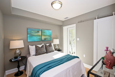 Ejemplo de habitación de invitados actual con paredes grises y suelo de madera clara