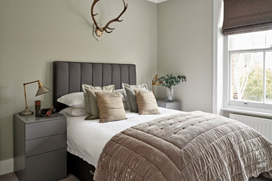 This is an example of a medium sized contemporary guest bedroom in London with grey walls, carpet and grey floors.