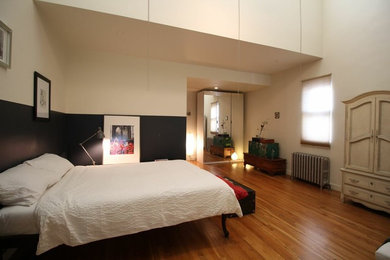 ニューヨークにある広いミッドセンチュリースタイルのおしゃれな客用寝室 (ベージュの壁、無垢フローリング、暖炉なし)
