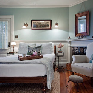 Imagen de habitación de invitados de estilo de casa de campo con paredes azules, suelo de madera en tonos medios y chimenea de esquina