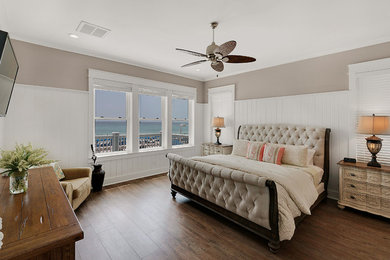 Diseño de dormitorio principal costero de tamaño medio sin chimenea con paredes beige, suelo de madera en tonos medios y suelo marrón