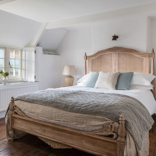 This is an example of a romantic bedroom in Cornwall with white walls, dark hardwood flooring and brown floors.