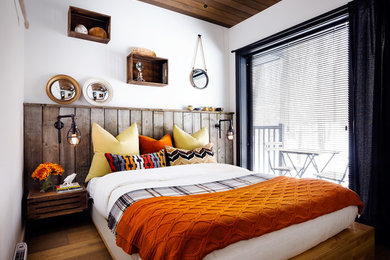 This is an example of a small rustic guest bedroom in Toronto with white walls and medium hardwood flooring.
