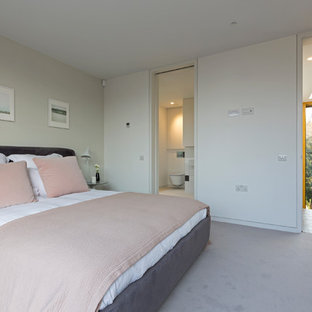 Photo of a medium sized contemporary grey and pink bedroom in London with white walls, carpet, grey floors and a feature wall.
