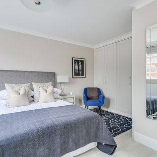 This is an example of a medium sized traditional bedroom in London with beige walls and grey floors.