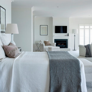 This is an example of a beach style bedroom in Other with white walls, carpet, a standard fireplace and grey floor.
