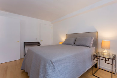 Imagen de dormitorio principal contemporáneo con paredes blancas y suelo de contrachapado
